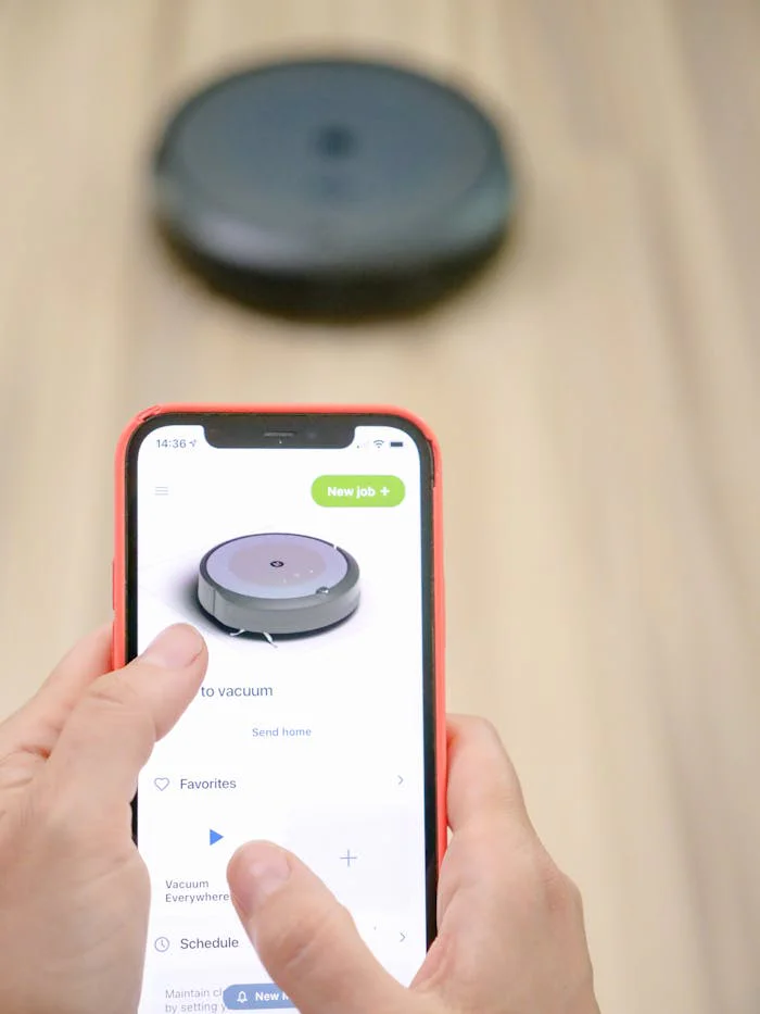 User operates robotic vacuum via smartphone app, showcasing smart home technology.