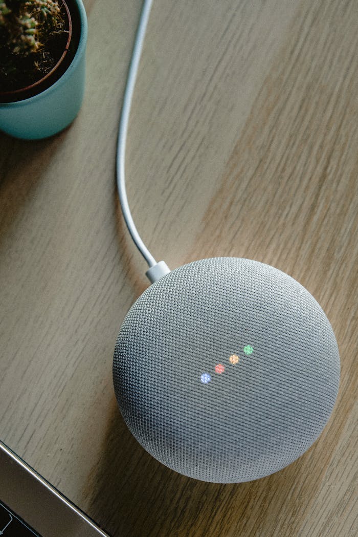 A top view of a smart speaker with a glowing indicator on a desk, emphasizing modern technology.
