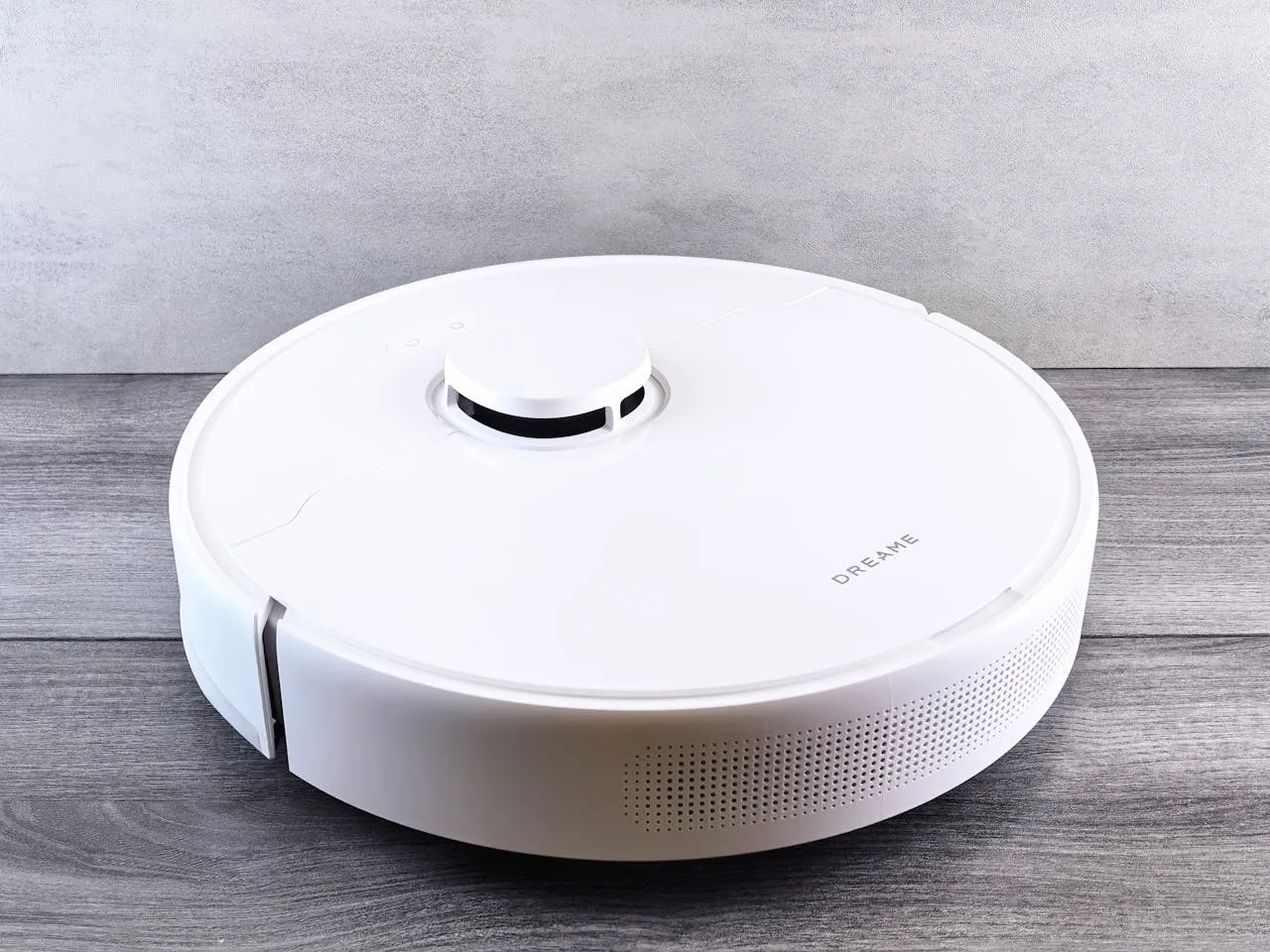 Sleek white robot vacuum cleaner on a wooden floor, perfect for smart home setups.